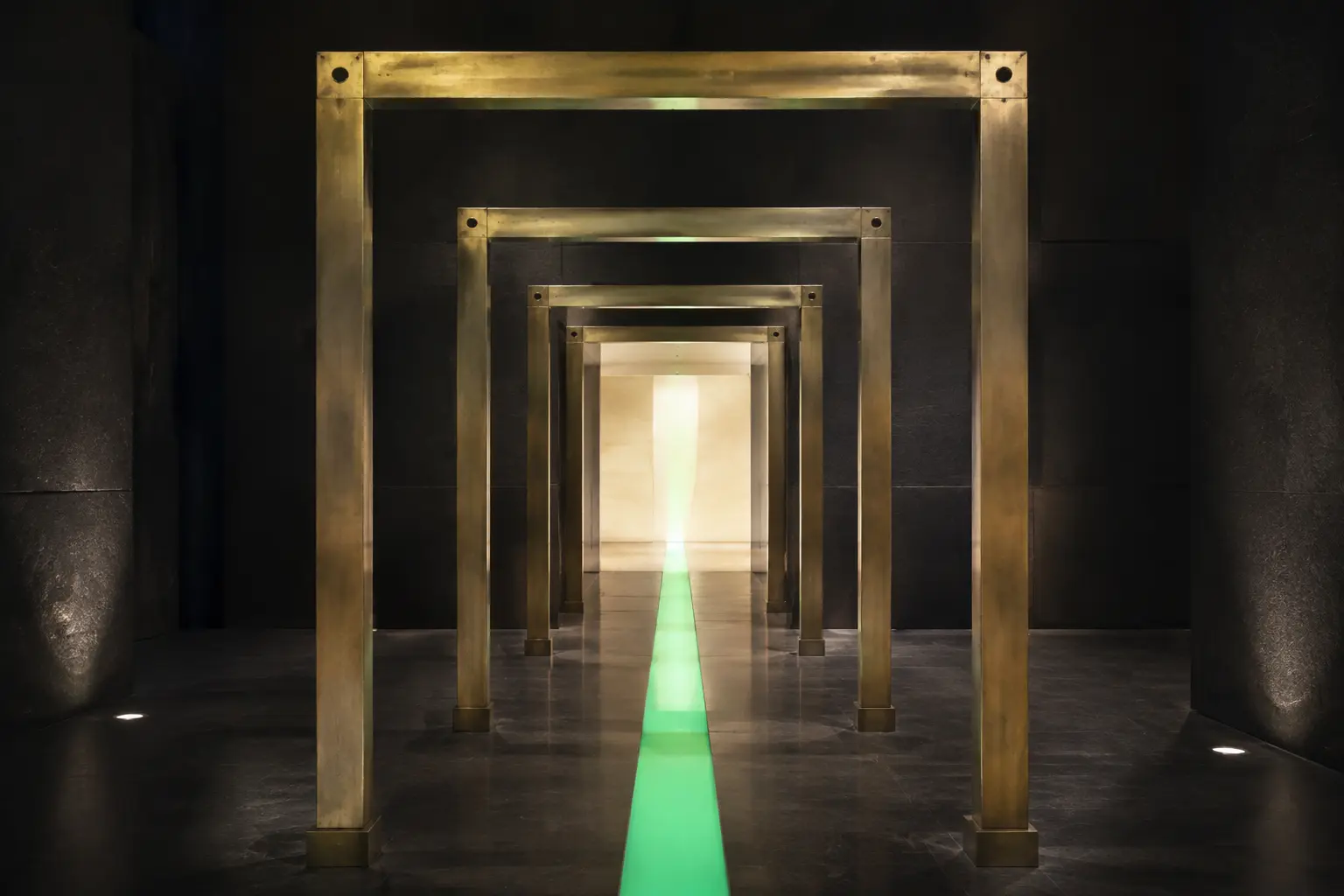 Four aligned brass gates crossed by a green beam toward a bright chamber